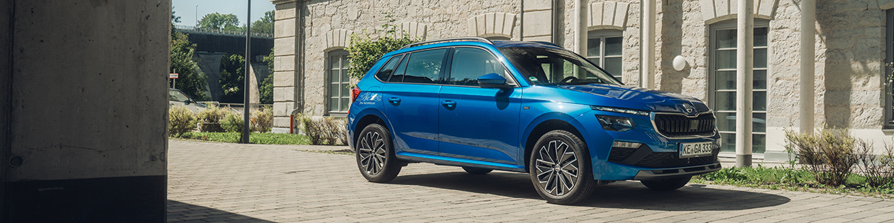 Ein blauer Skoda Kamiq steht auf einer Einfahrt vor einem Wohngebäude